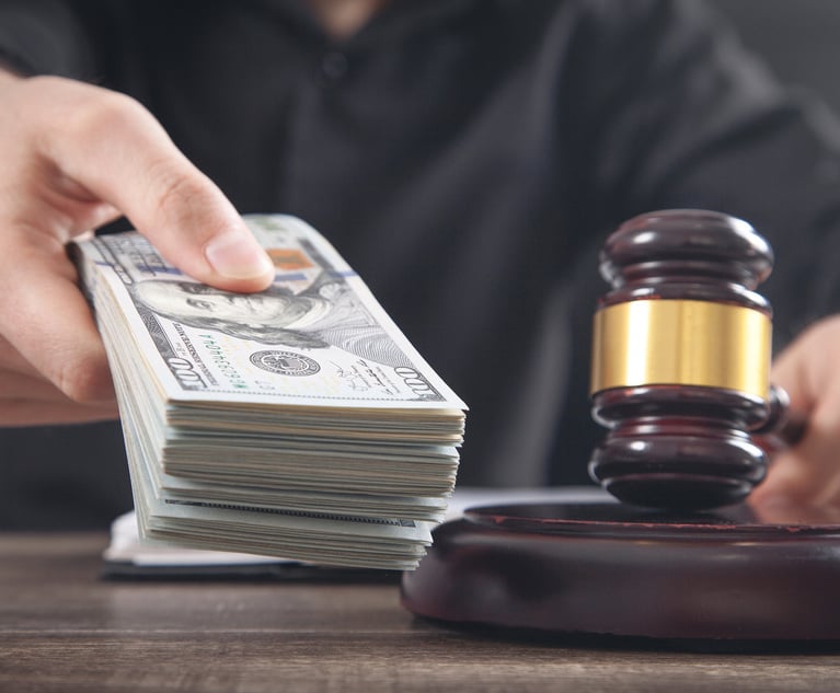 A judge holding a gavel while holding out a stack of money