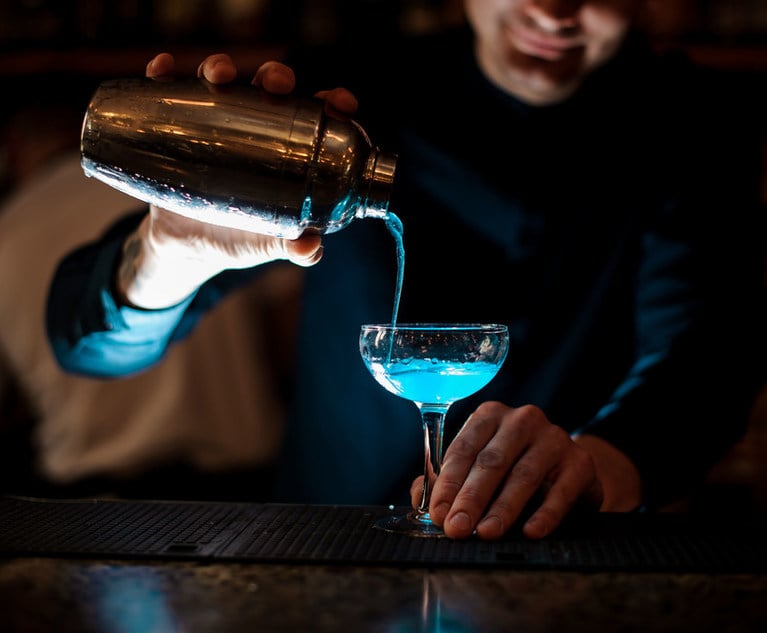 A close-up of a bartender pouring a blue drink