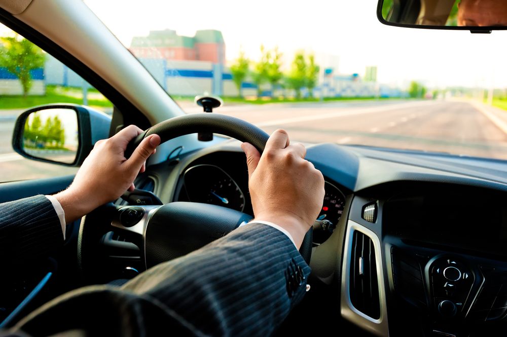 Man's hands on car steering wheel