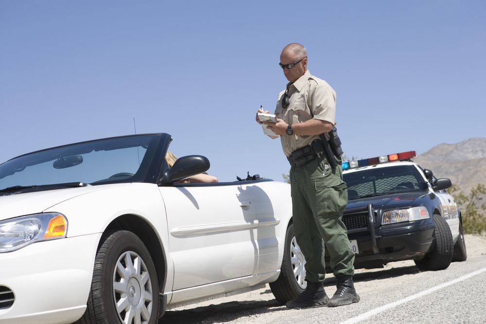 woman in white convertible getting traffic ticket from a sheriff deputy