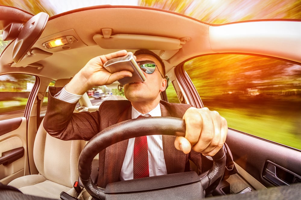 man drinking while driving a car