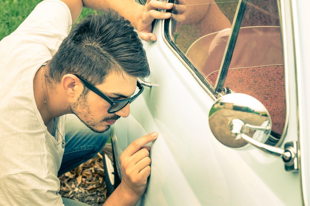 man inspecting small car dent