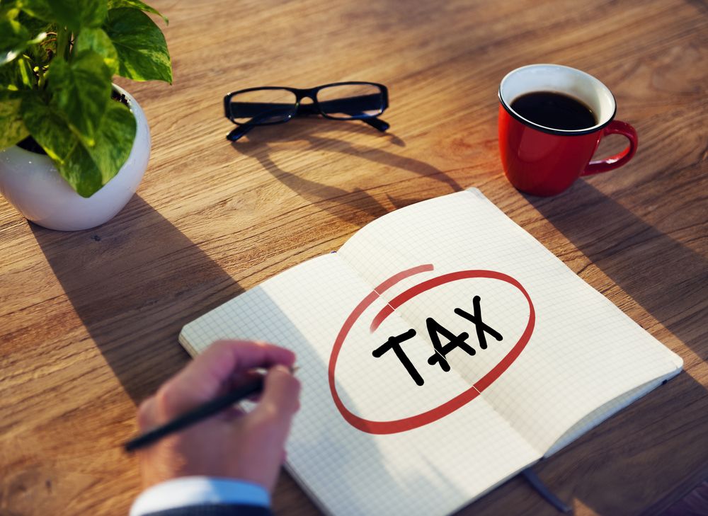 businessman writing tax in notebook