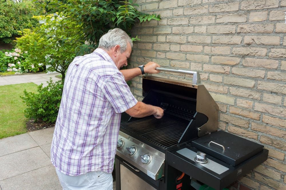 man cleaning outside grill