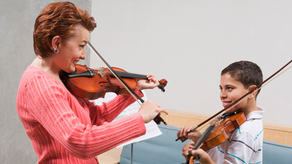 Violin music teacher working with young student