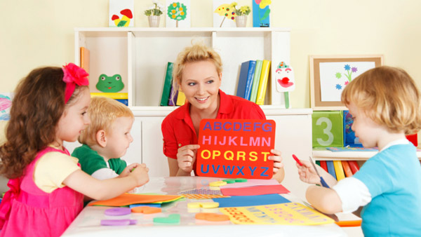 Preschool teacher teaching the alphabet to young children