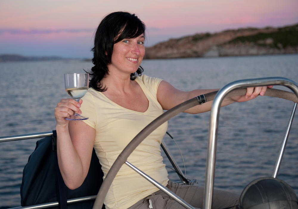 Young-woman-at-wheel-of-boat-with-wine-glass-shutterstock_58347451-Ventura