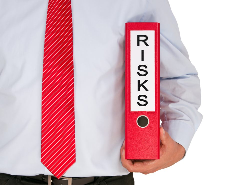 Man holding red notebook labeled Risks