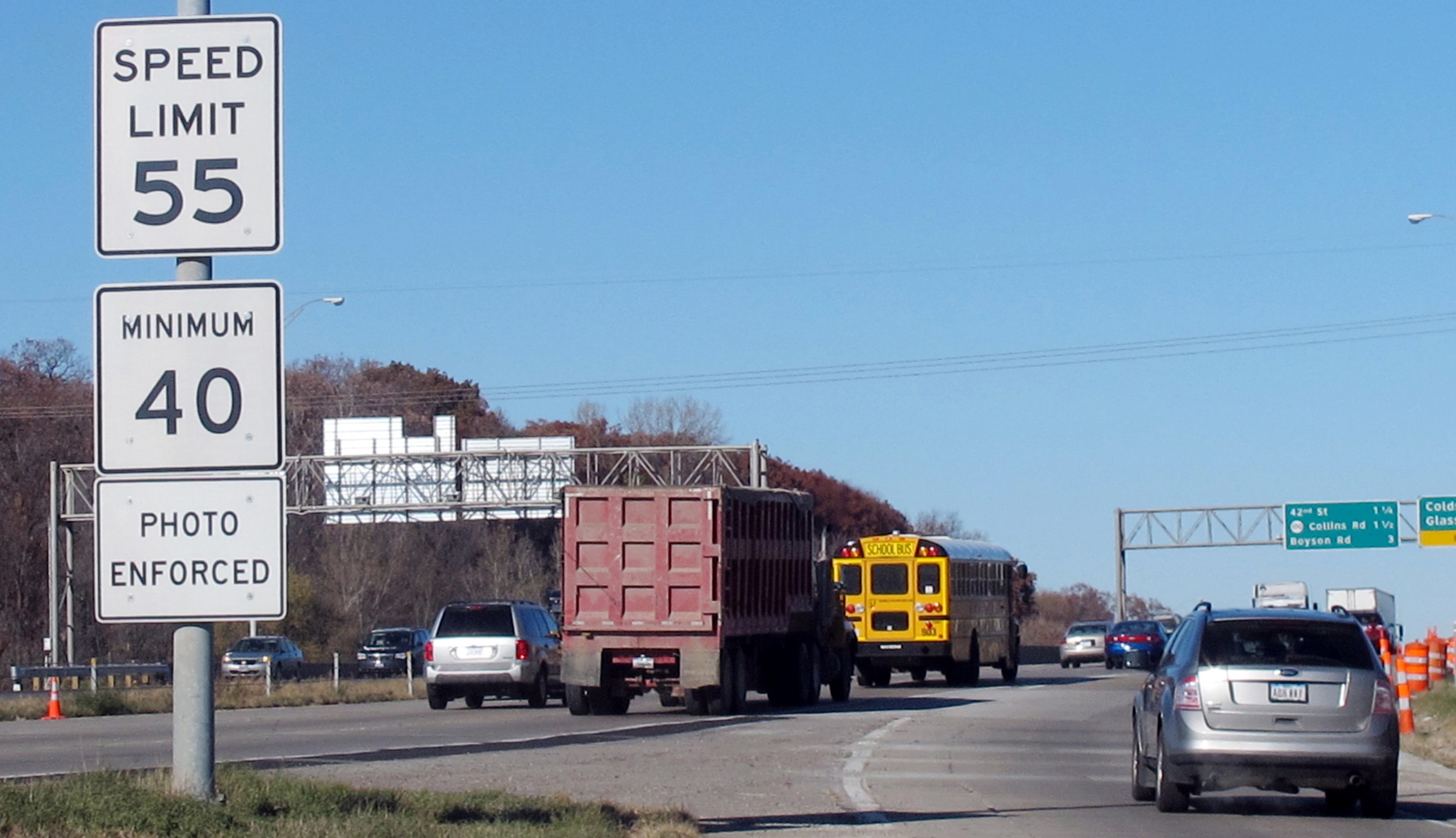  vehicles pass a highway sign along Interstate 380 in Cedar Rapids, Iowa, warning drivers that the 55-mph speed limit is enforced by speed cameras.