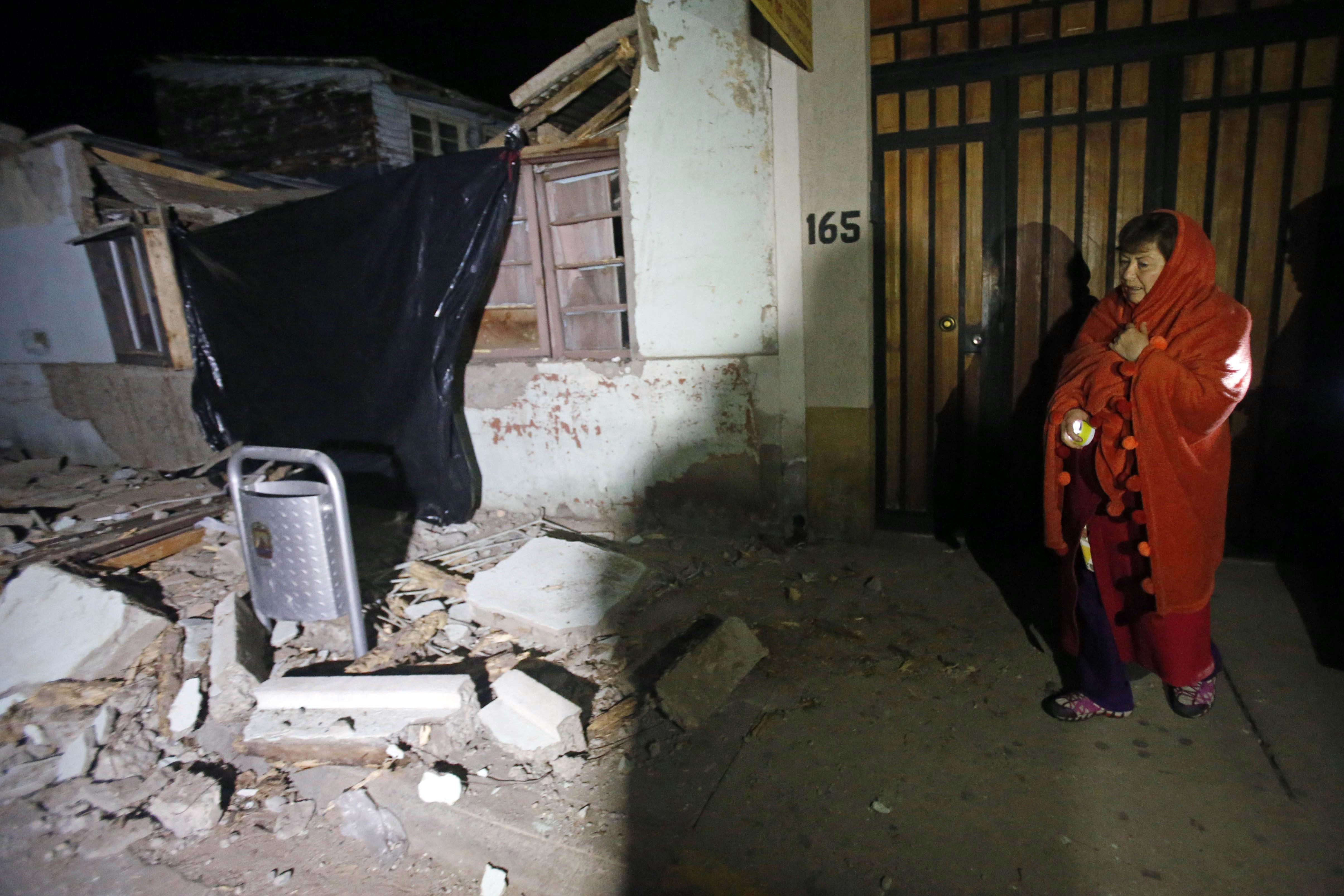 A woman stands outside a destroyed house in Illapel, Chile, Thursday, Sept. 17, 2015. 