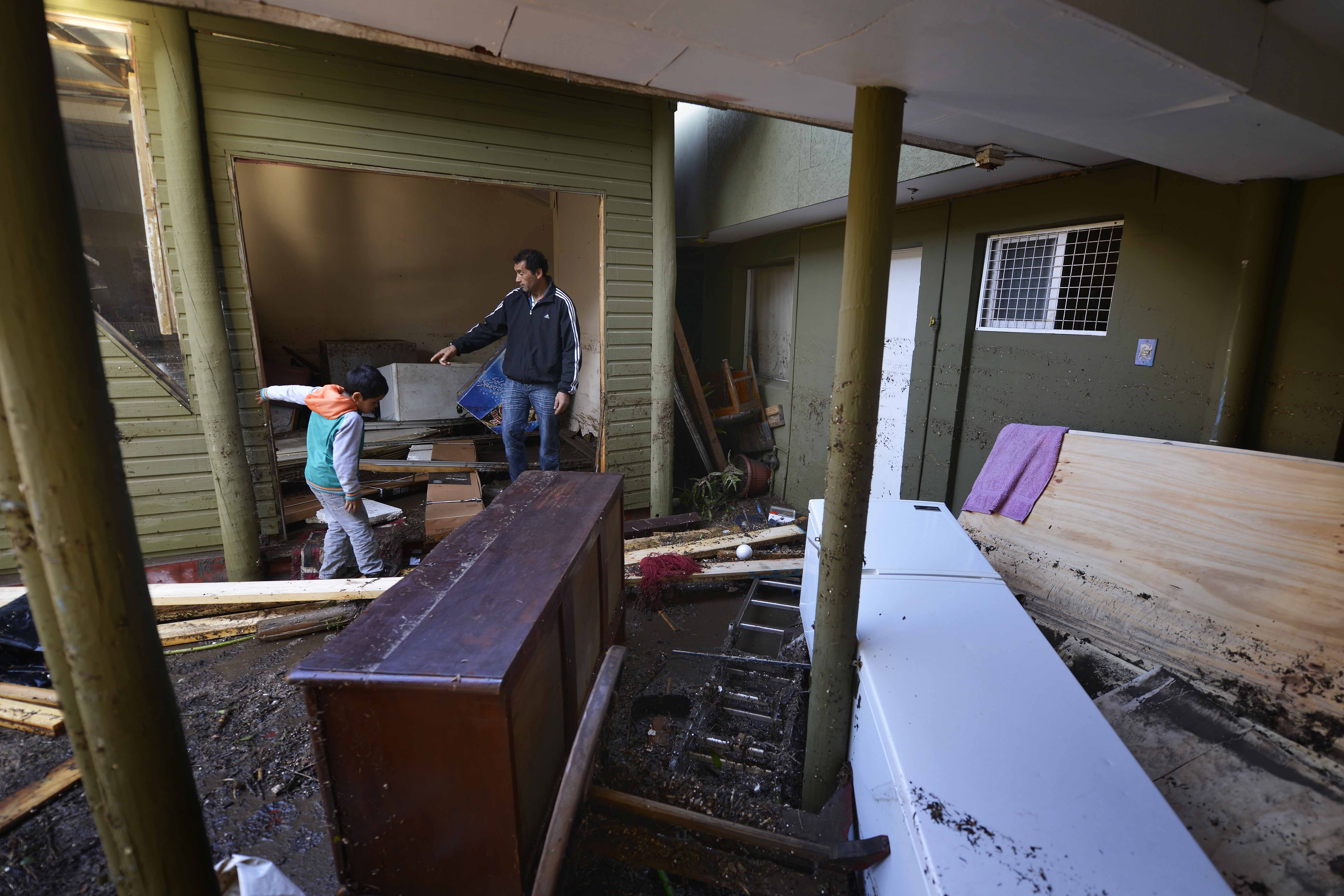 People stand inside a home destroyed by an earthquake-triggered tsunami in Concon, Chile