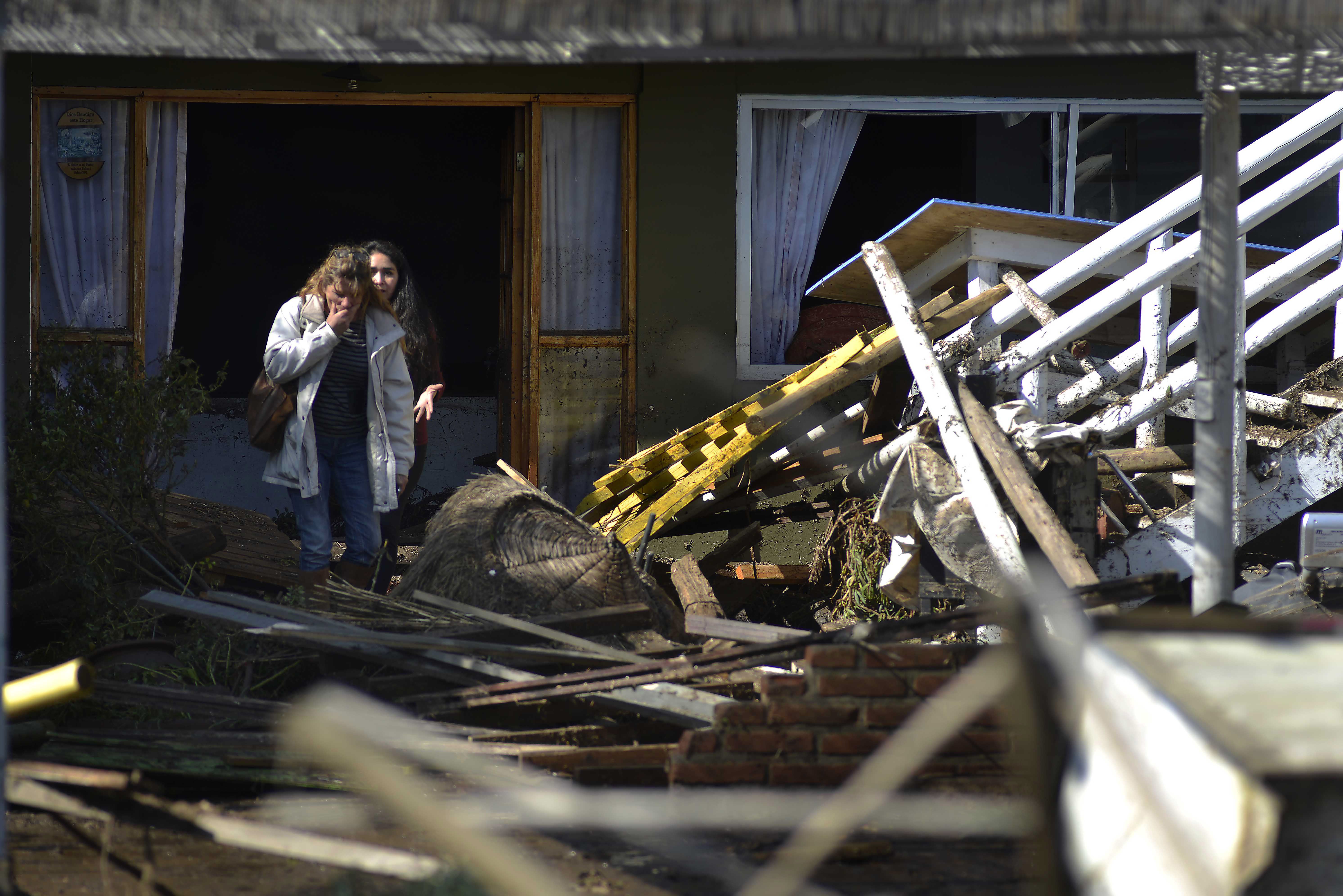 Women look a the destruction left behind by an earthquake-triggered tsunami in Concon, Chile