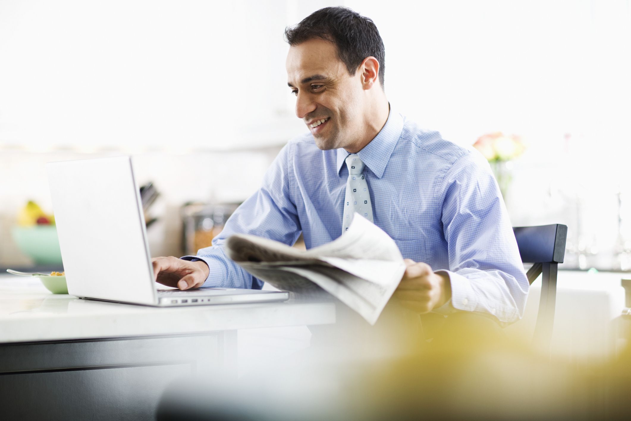 business man working on a laptop with newspaper