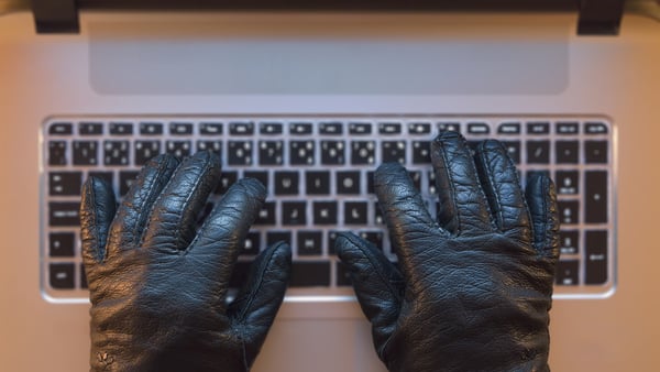 hacker with black gloves typing on keyboard