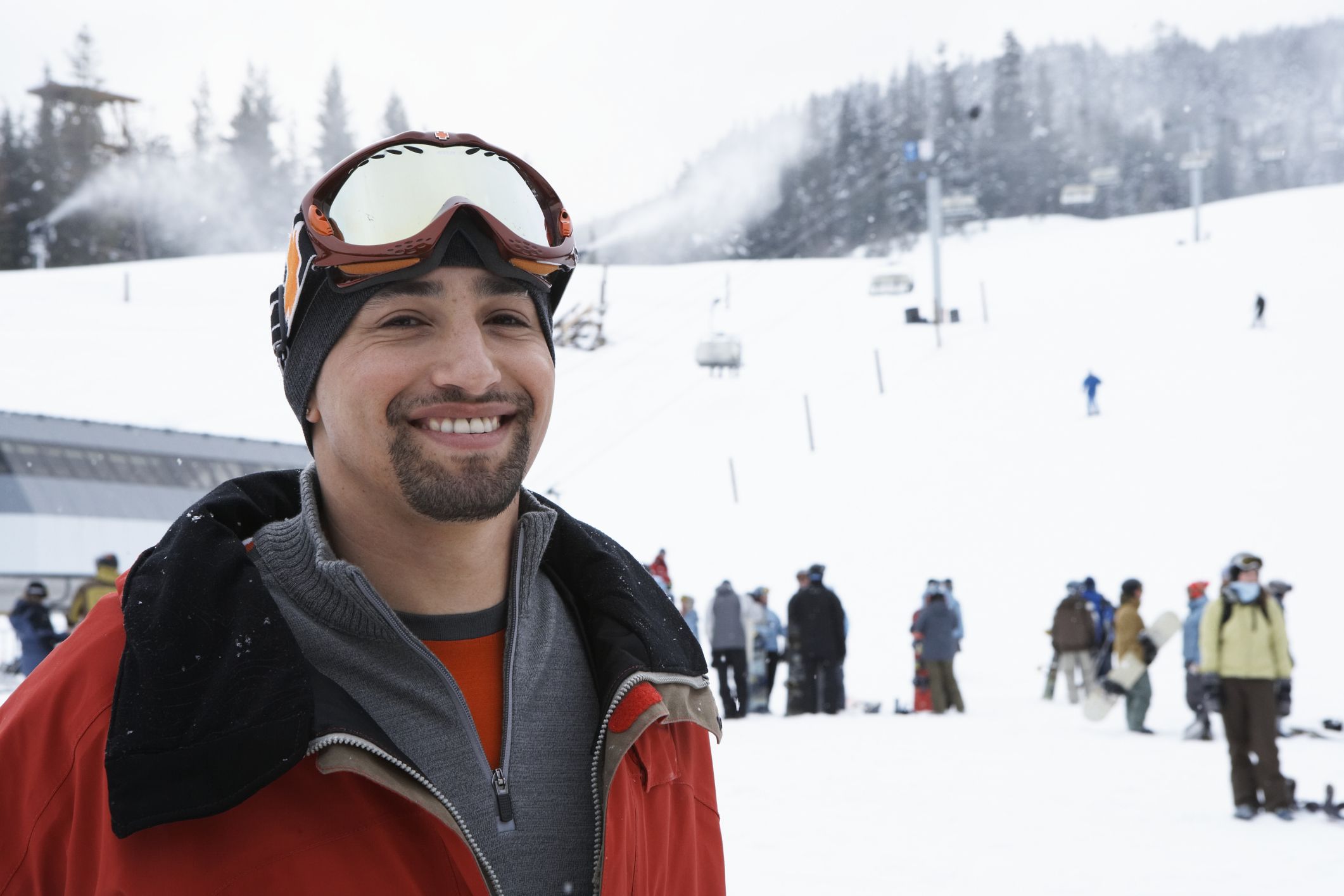 Man standing near ski lift at base of mountain with layered clothing