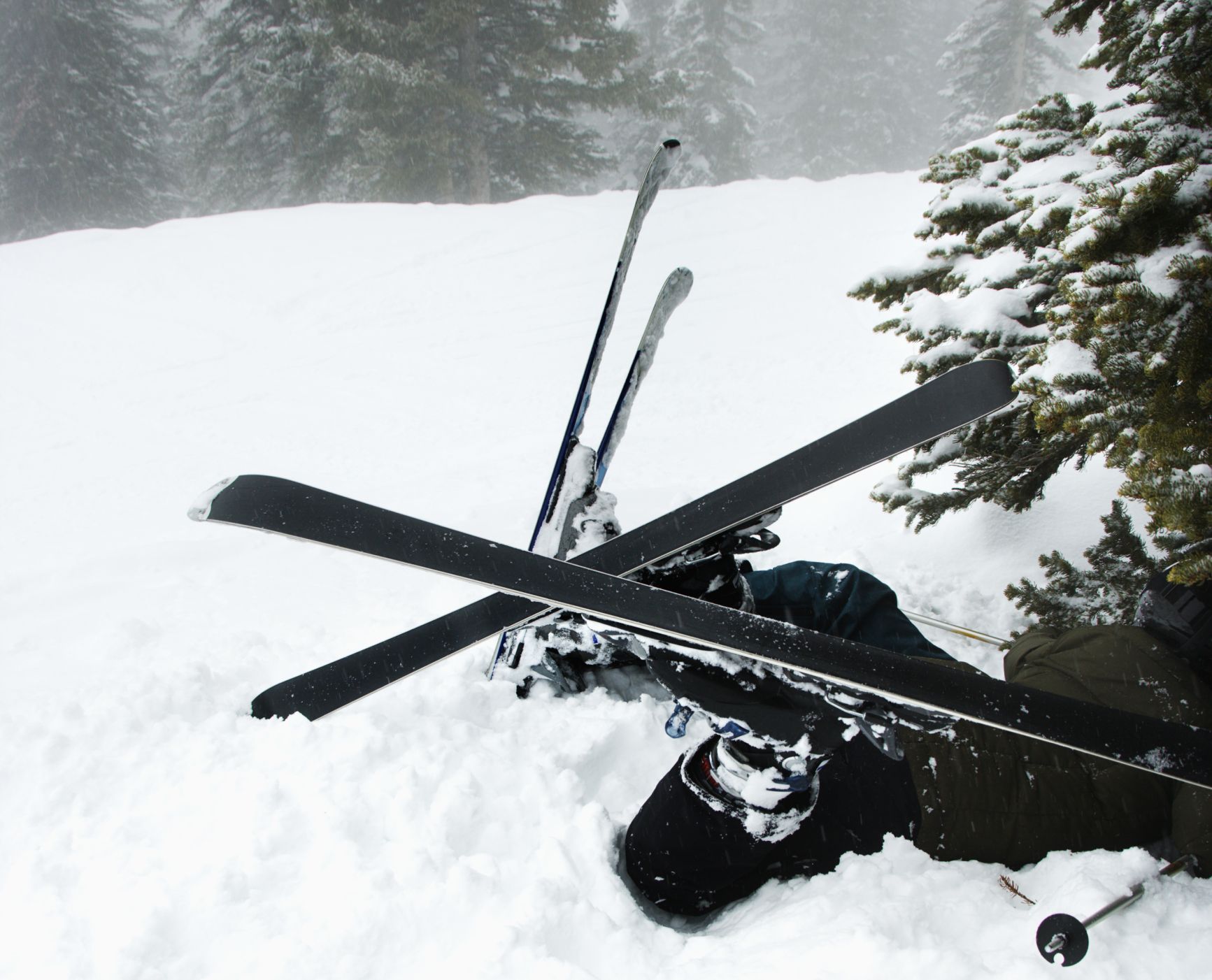 Skiers lying in snow near tree after crash in fog