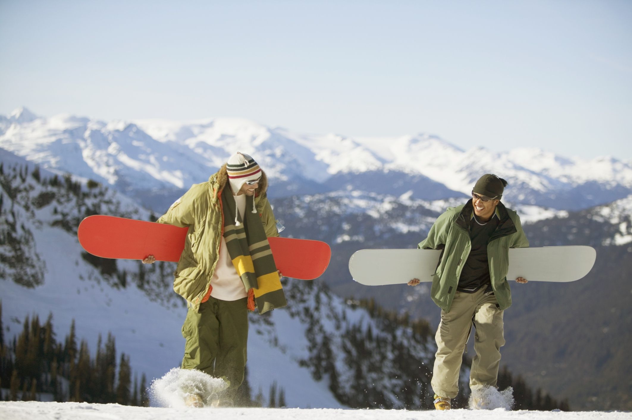 2 snowboarders carrying their boards