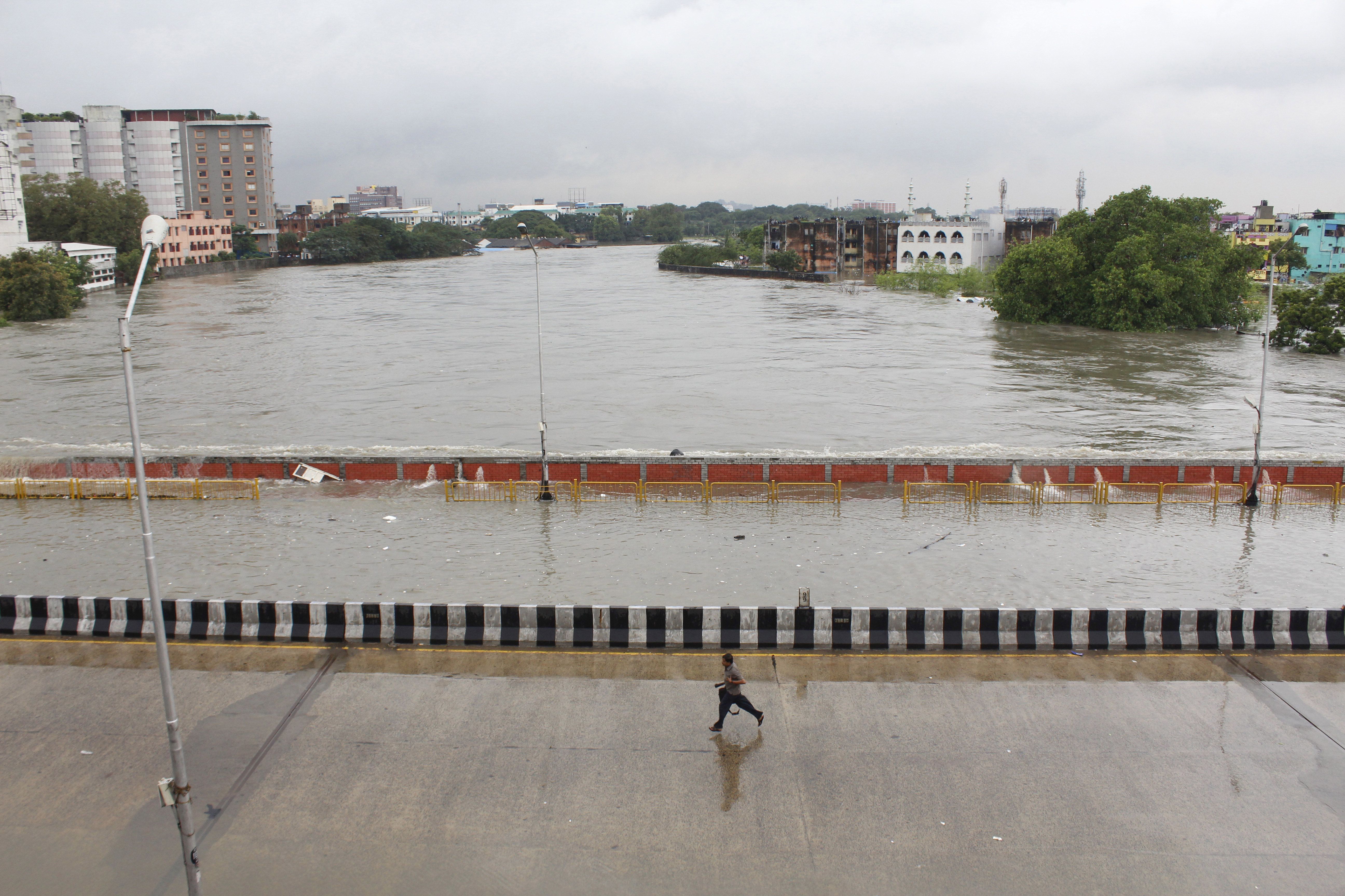 A man runs through a bridge across an over-flowing Adyar River in Chennai, Tamil Nadu, India, Wednesday, Dec. 2, 2015.