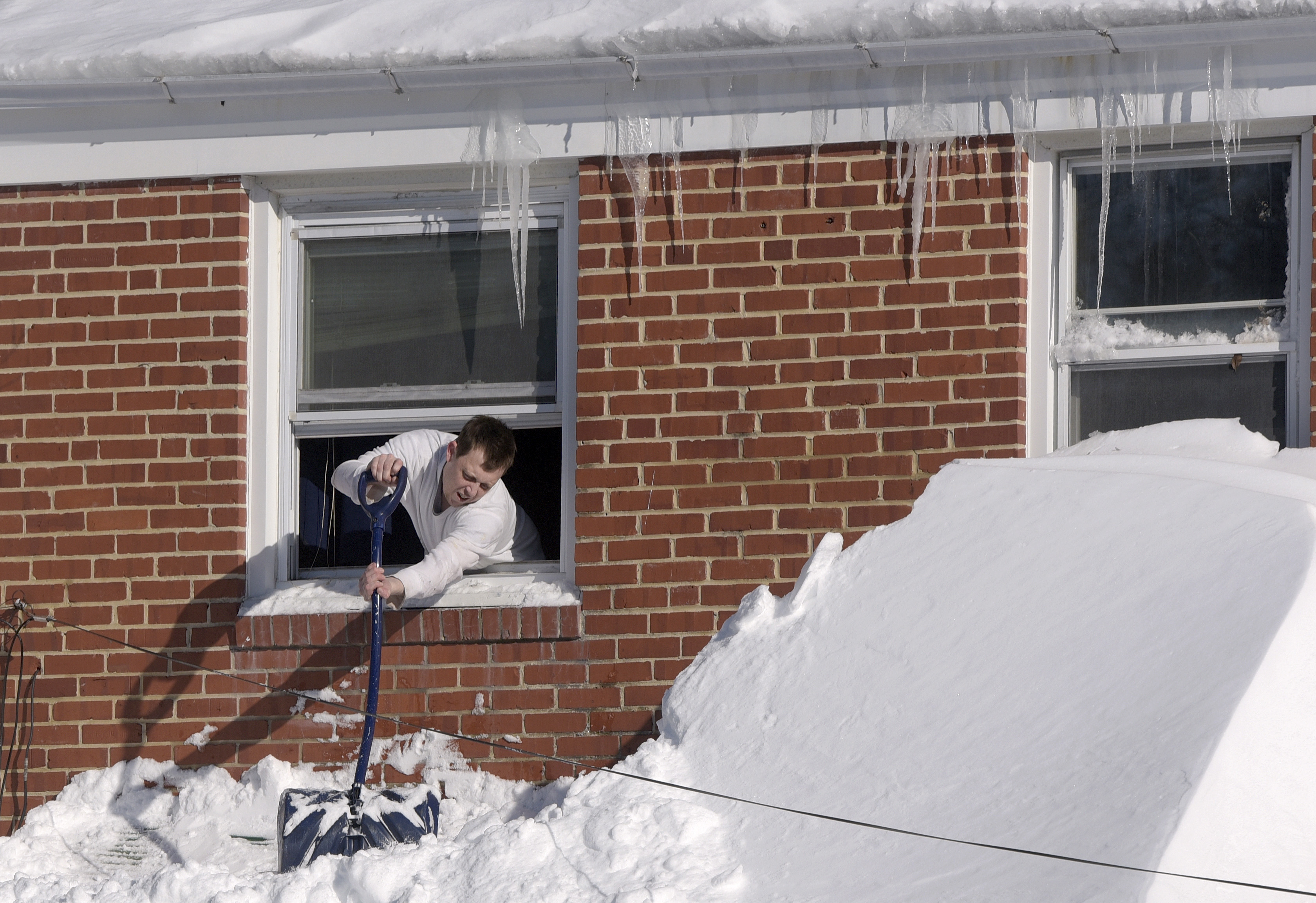 Man-clearing-snow-off-house-awning-from-second-floor-window-Blizzard-Jan-2016-crop-AP_197529660047-Steve Ruark