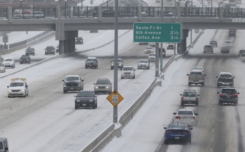 Motorists proceed along the slick roadway of Interstate 25 as high winds drive granular snow into drifts Tuesday, Dec. 15, 2015, in Denver. 