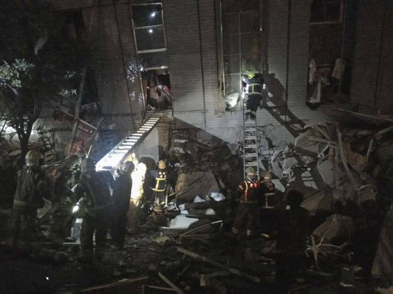 Rescuers are seen entering an office building that collapsed on its side from an early morning earthquake in Tainan, southern Taiwan