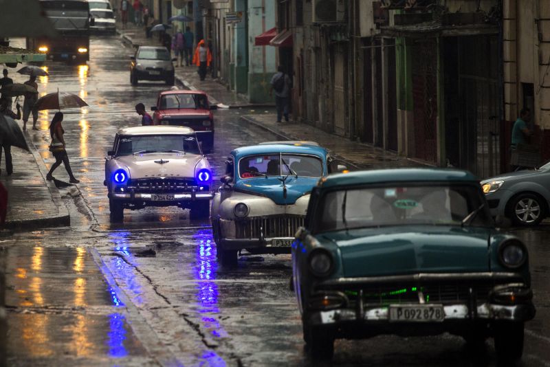 Cars drive along Neptuno Street as it rains in Havana, Cuba