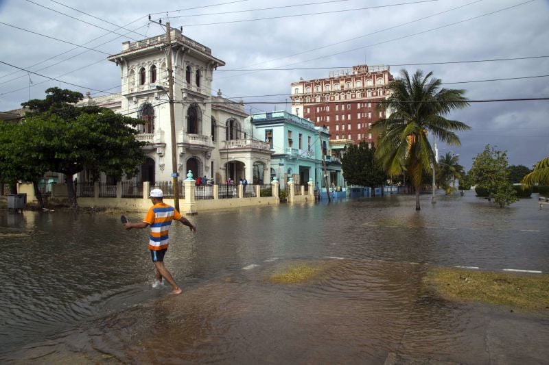 A pedestrian wades through a flooded portion of Avenida de los Presidentes, in Havana, Cuba, Saturday, Jan. 23, 2016. 