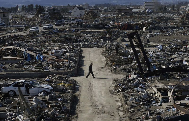  man walks through the destroyed neighborhood below Weather Hill in Natori, Japan.