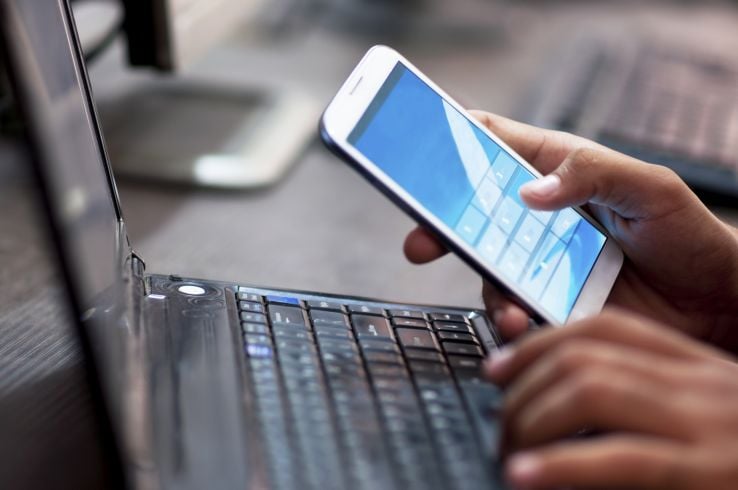 Man using cellphone and laptop