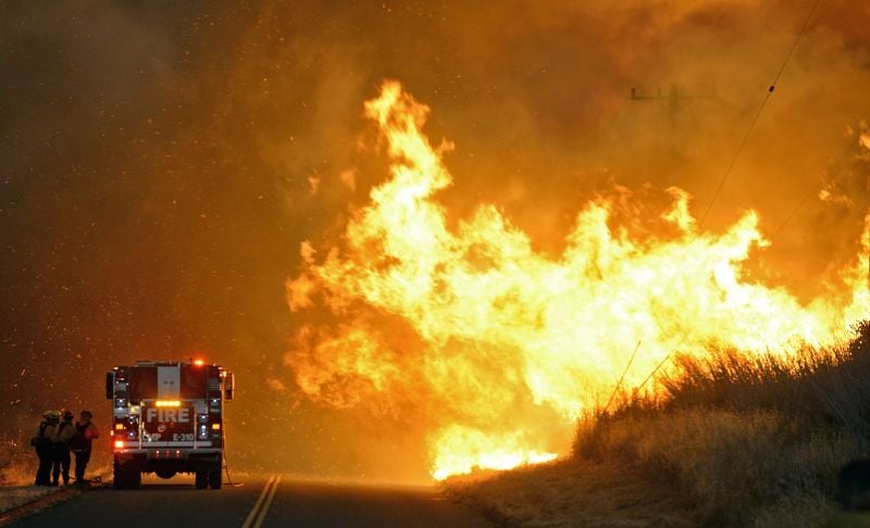 Firefighters from the Lompoc City Fire Department take shelter behind their engine