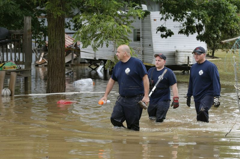 Bridgeport W.Va. firefighters walk through a flooded street while searching homes in Rainelle, W. Va