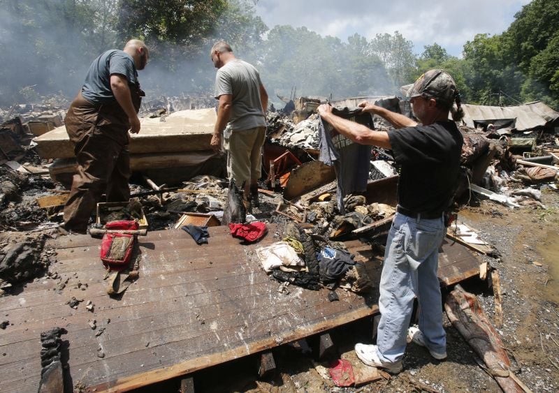 Ron Scott, right, recovers a shirt from the burned remnants of his home 