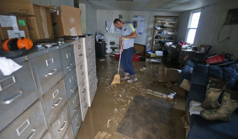 Shane Altzier starts to sweep out the mud from the town utilities office in Rainelle, W. Va.