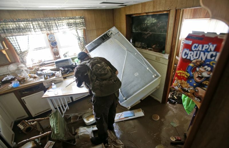 West Virginia Natural Resources police officer Chris Lester searches a flooded home