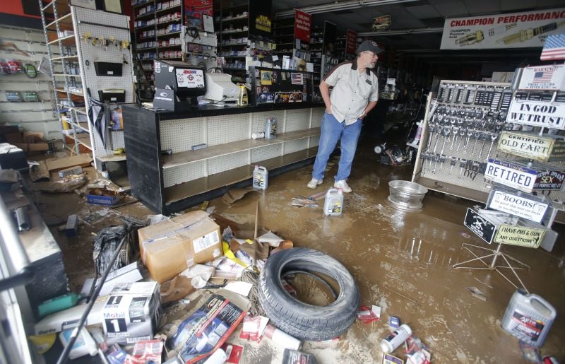 Paul Raines looks over his flooded Western Auto store in Rainelle, W. Va.