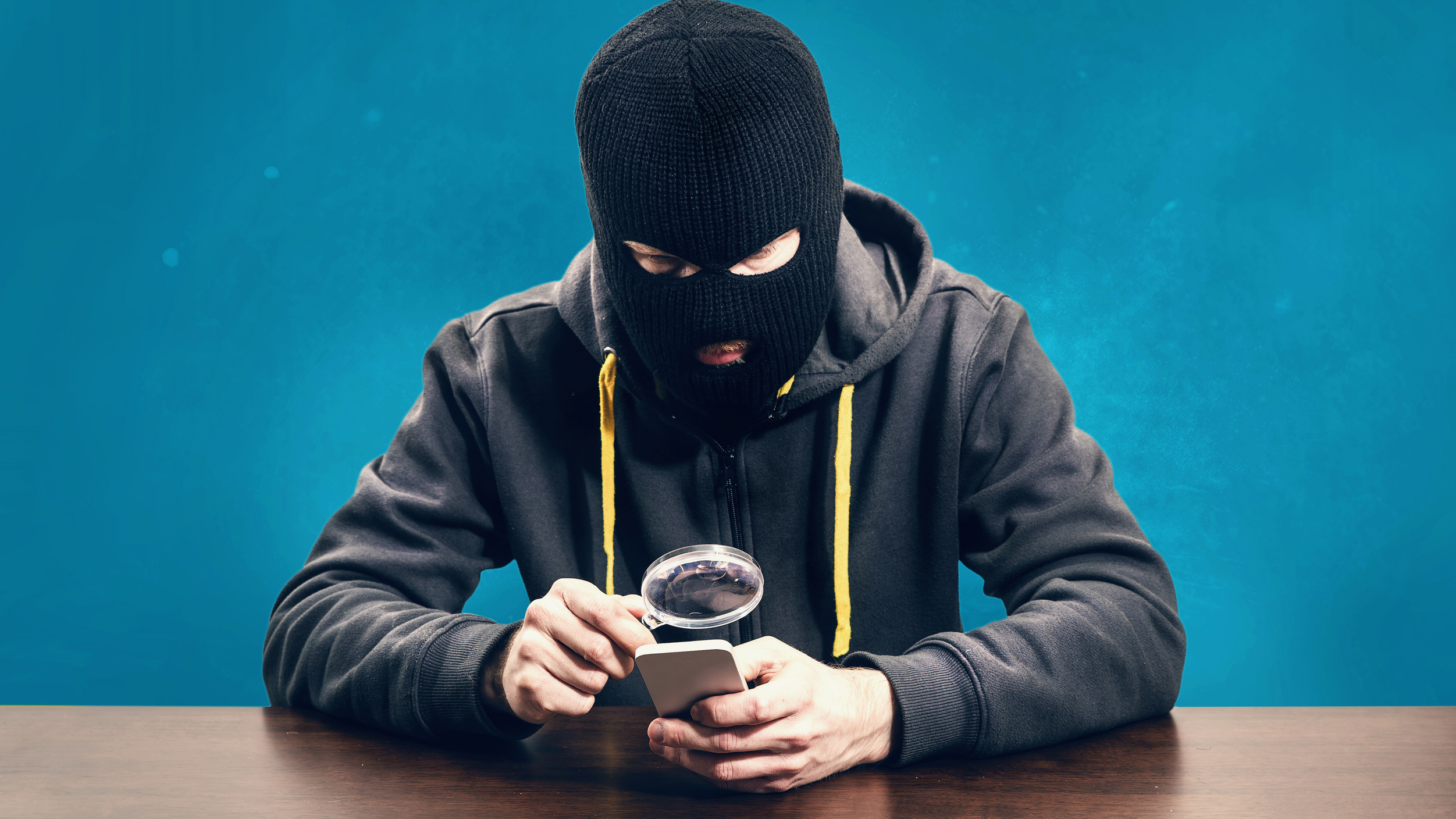 Hacker-inspecting-smartphone-with-magnifying-glass-iStock