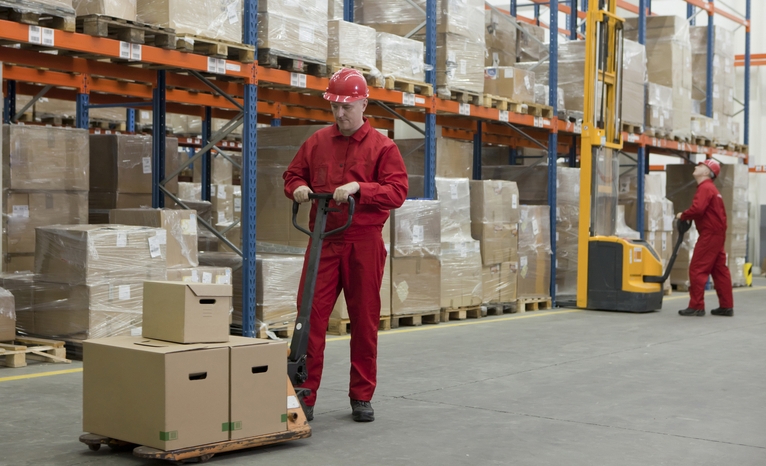 Men moving boxes in warehouse with equipment