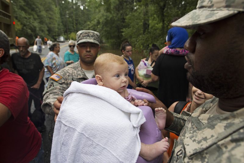 Members of the Louisiana Army National Guard load three-month-old baby Ember Blount onto a dump truck