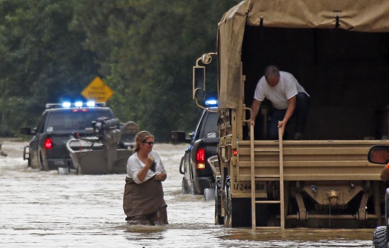 Jeff Robinson lowers a ladder from a Louisiana National Guard truck as his wife wades through flood waters 