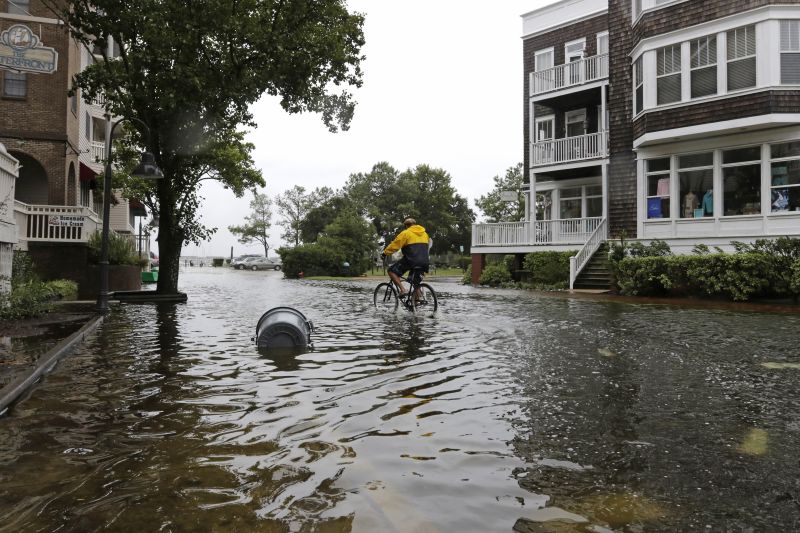 Stevie Green rides a bike on the flooded streets of downtown Manteo, N.C.