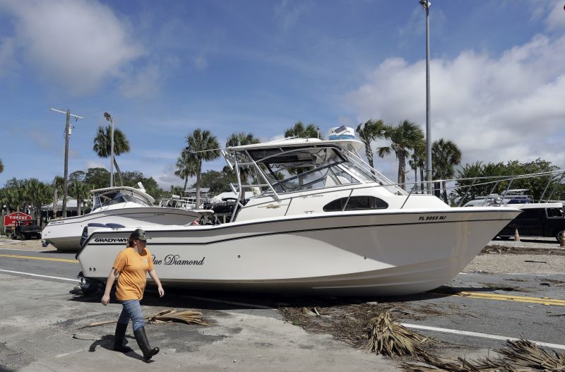 A woman walks past pleasure boats that were washed into Riverside Dr., when Hurricane Hermine came ashore early Friday, Sept. 2, 2016, in Steinhatchee, Fla. 