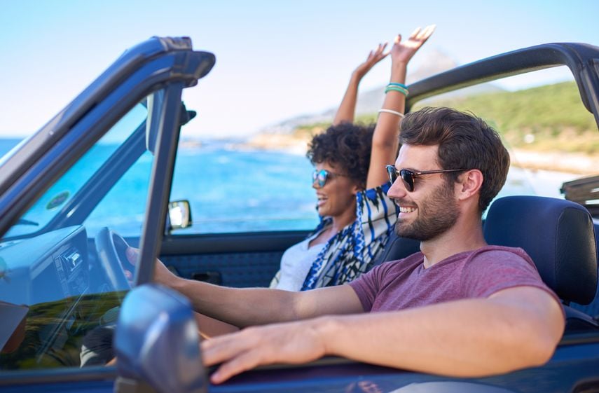 couple driving by the ocean in a convertible