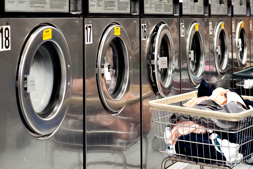 Row of washers and dryers with basket of laundry