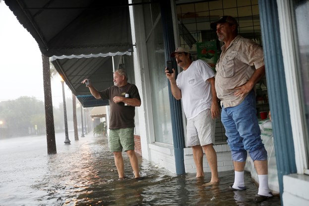 3 men taking pictures flooded street Hurricane Matthew