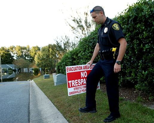 Police officer with evacuation no trespassing sign flooded street