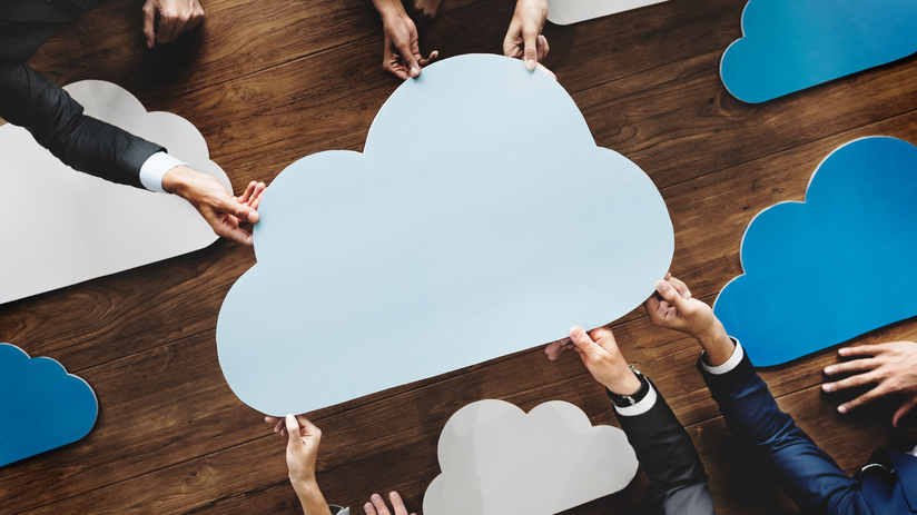 Hands around a table holding a cloud cut-out