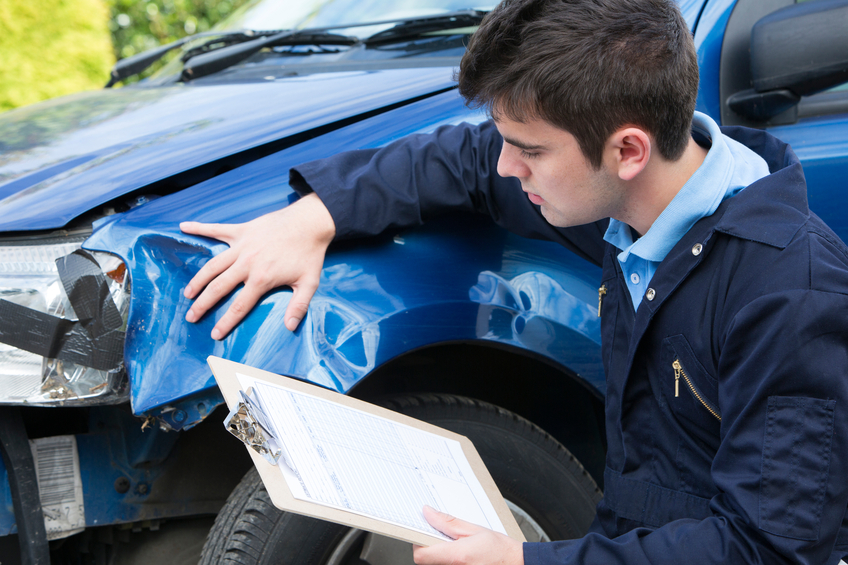 claims adjuster looking at car