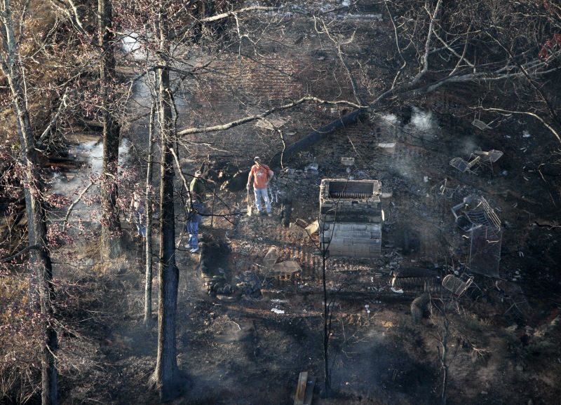 People inspect the remains of a home burned by a wildfire