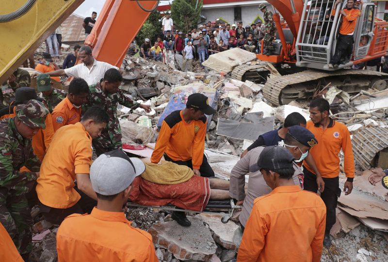 Rescuers recover the body of a victim from the rubble of a collapsed building after an earthquake