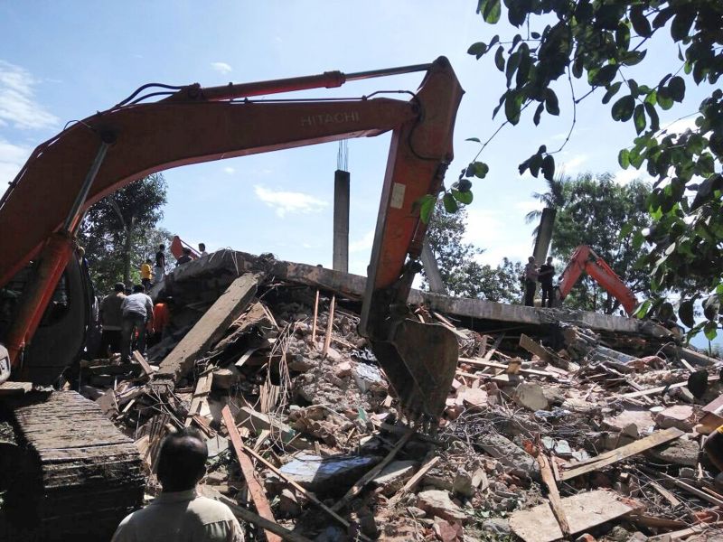 Rescuers use heavy machine to search for survivors under the rubble of a collapsed building after an earthquake 